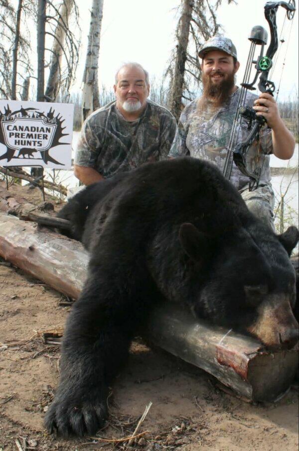 Robert Wood (L) and his son T.J. Wood display a bear taken during a hunting trip. (Steve Murphy)