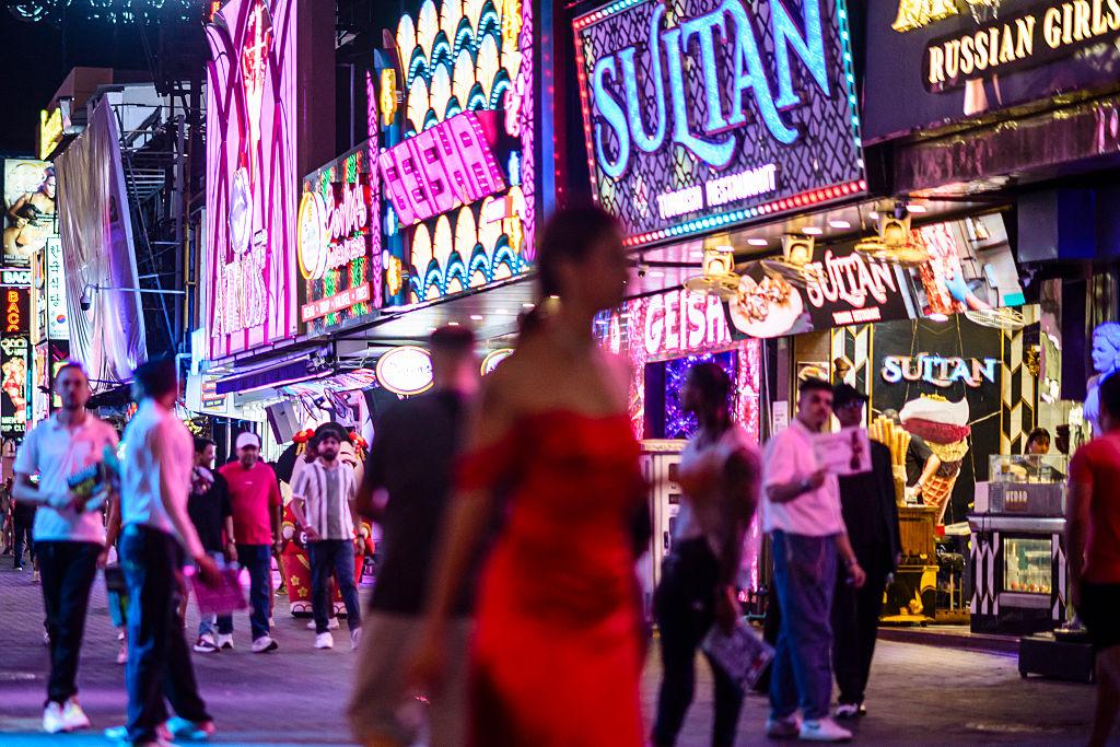People walk past bars and clubs along Walking Street in Pattaya, Thailand on July 3, 2026. Scantily dressed and wearing stiletto heels, hundreds of girls, some apparently very young, form a seedy guard of honour under the lights of Soi 6, a street in one of Pattaya's red-light districts. (Anthony Wallace/AFP via Getty Images)