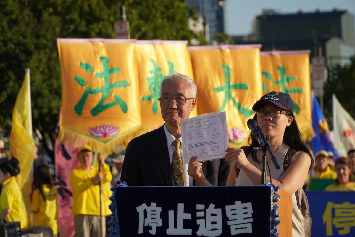Hao Fangfang (R) holds up her certificate declaring her decision to quit the Chinese Communist Party and its affiliated organizations, while Wang Zhiyuan (L), chairman of the Global Service Center for Quitting the CCP, looks on, in New York City on July 20, 2026. (Nicholas Zifcak/The Epoch Times)