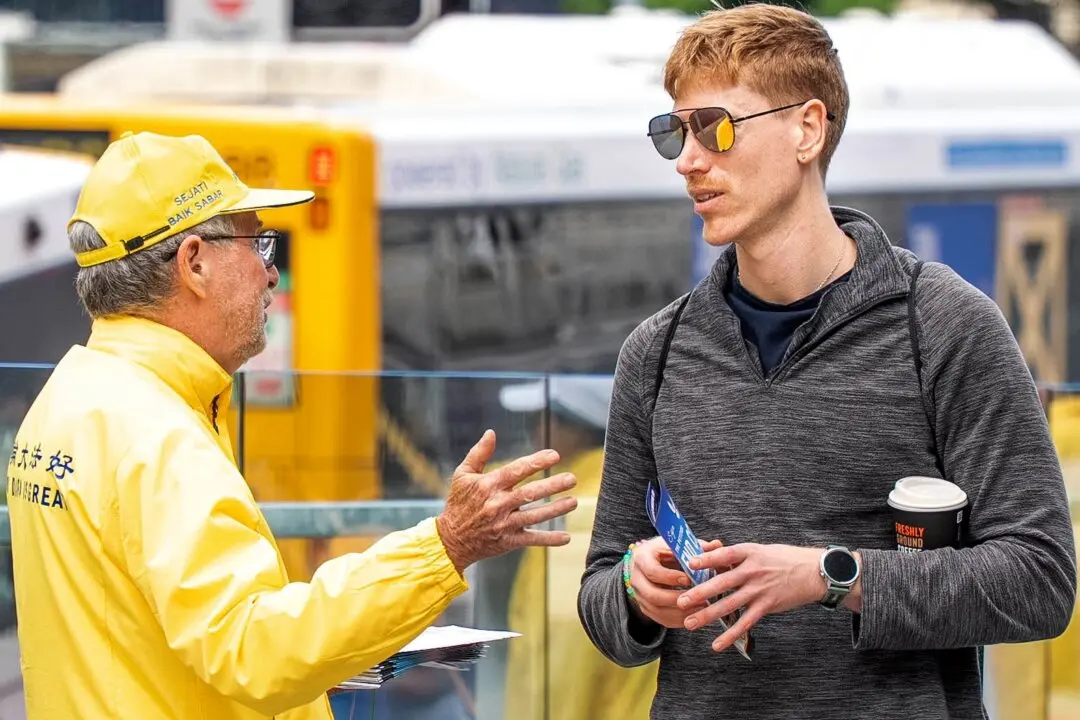 A volunteer speaks with a member of the public ahead of the July 20th global appeal in Brisbane on July 18, 2026. (Hong Yuan/NTD)