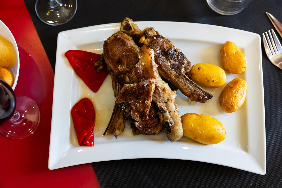 A plate of roasted Aragonese lamb ribs served with peppers and boiled potatoes. Roasted lamb is a regional specialty. (BearFotos/Shutterstock)