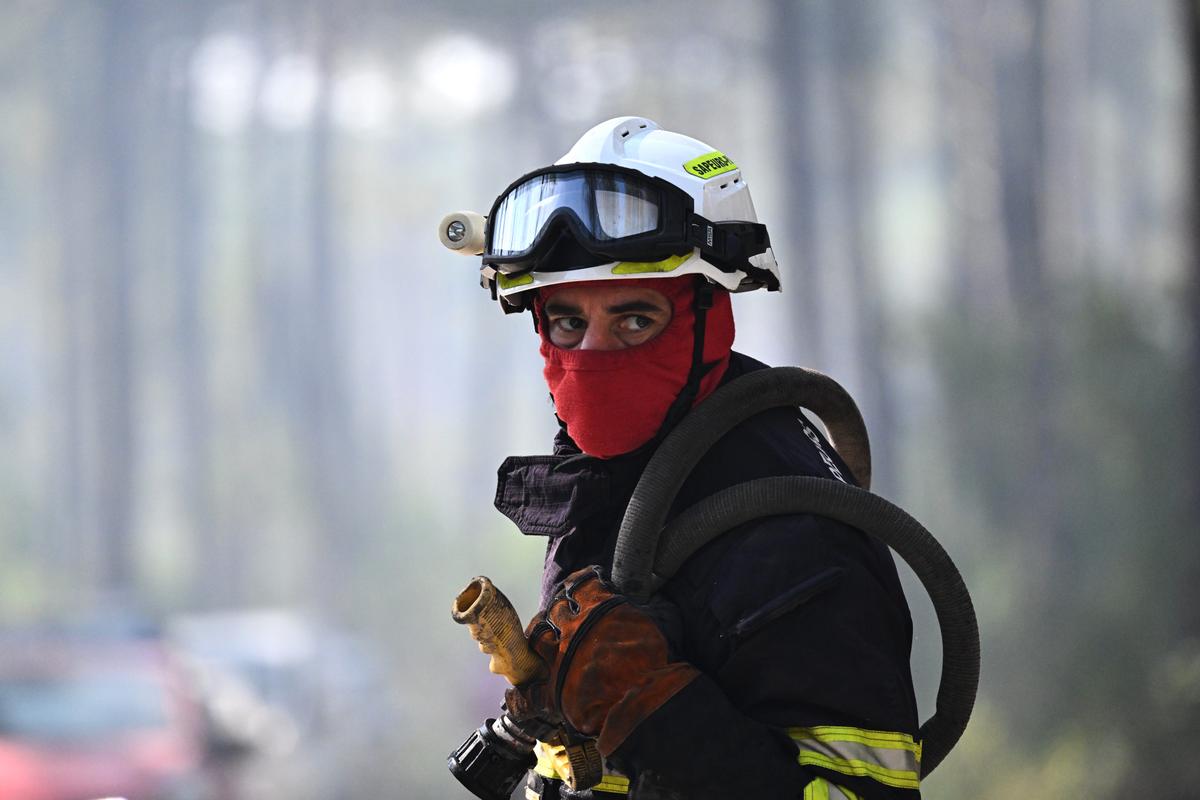 A firefighter carries his equipment as he works to suppress a fire in a forest in Claouey, during wildfires in the area of southwestern France, on July 28, 2026. (Emma Da Silva/AP)