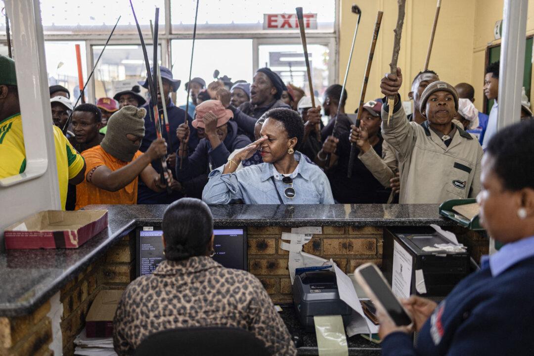 TOPSHOT - A woman reacts as protesters storm the Department of Home Affairs offices during a demonstration calling for the removal of undocumented immigrants in Alexandra township on July 30, 2026. South African President Cyril Ramaphosa called on July 27 for African countries to work together to manage migration, as his government faces mounting pressure over attacks on foreign nationals. Ramaphosa's appeal to the Pan-African Parliament follows weeks of anti-migrant protests in South Africa, where xenophobic activists and fringe groups have blamed undocumented migrants from elsewhere in Africa for crime, unemployment and strain on public services. (Photo by EMMANUEL CROSET / AFP via Getty Images)
