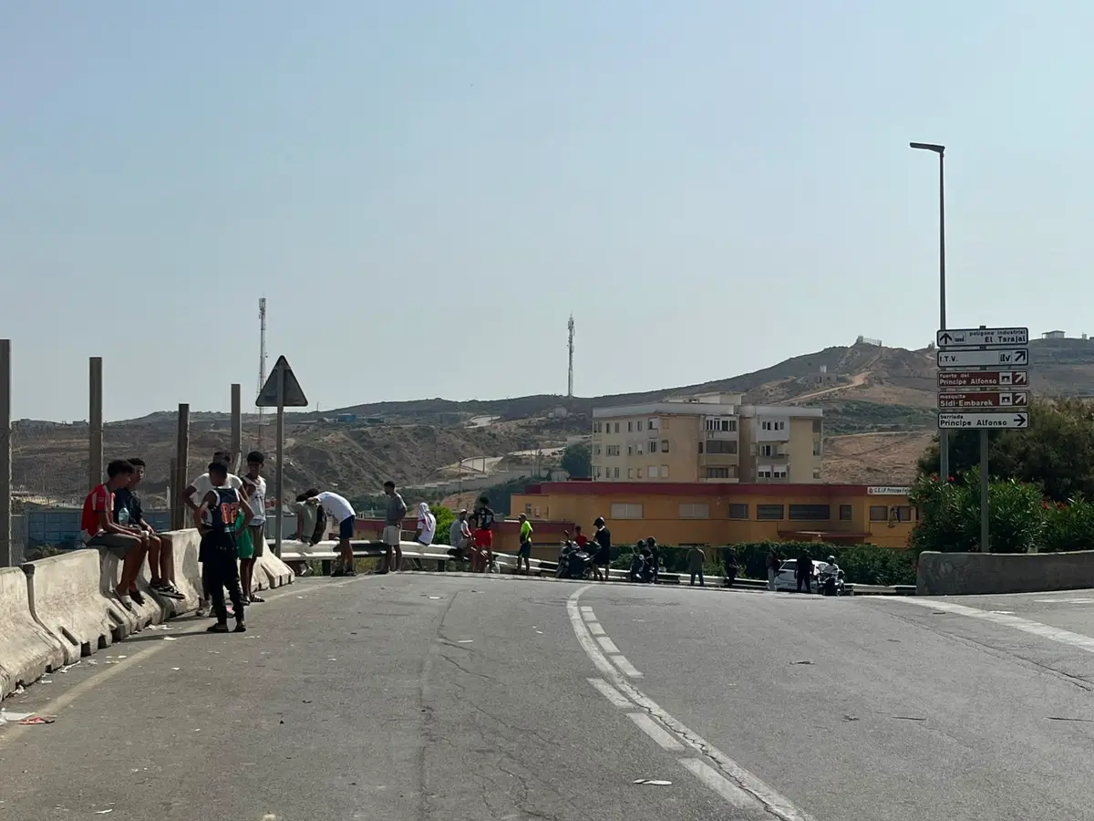 Young illegal immigrants gather near road signs pointing toward Príncipe Alfonso and El Tarajal in Ceuta, Spain, on Aug. 1, 2026. Several told The Epoch Times they planned to stay in the Spanish enclave. (Etienne Fauchaire/The Epoch Times)