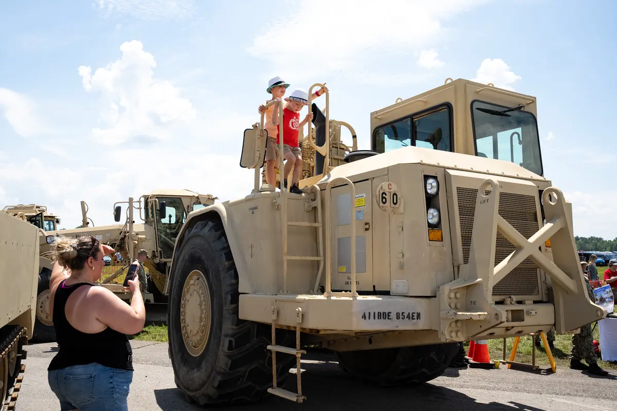 Fans climb on vehicles from the 417th Engineer Company at the U.S. Army Reserve Center in Montgomery, N.Y., on Aug. 1, 2026. (Larry Dye/The Epoch Times)