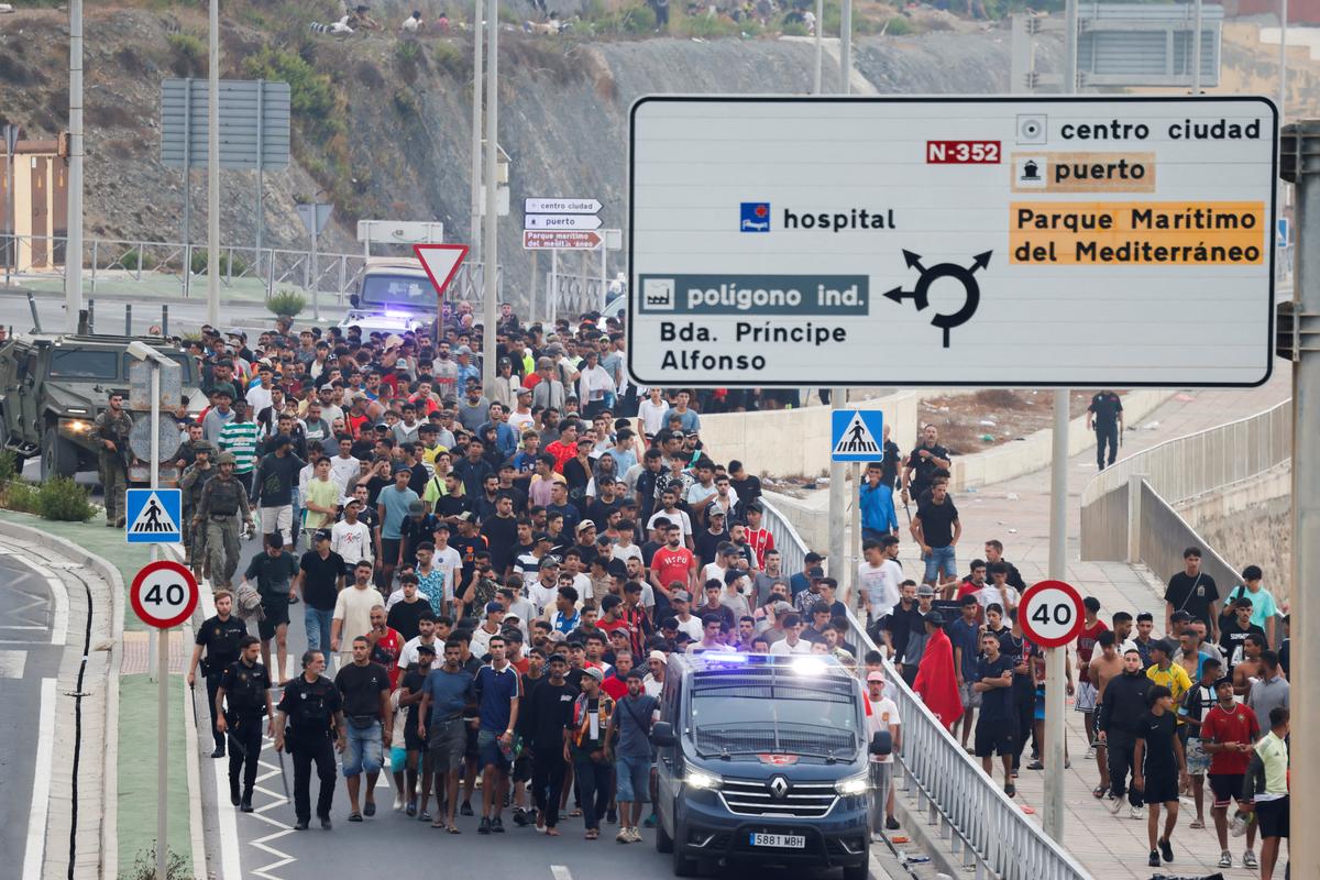 Police officers and Spanish soldiers escort a large group of illegal immigrants to the border to take them out of Spain, after mass crossings of migrants on foot and by sea from Morocco into Spanish territory, in Ceuta, Spain, on Aug. 1, 2026. (Jon Nazca/Reuters)