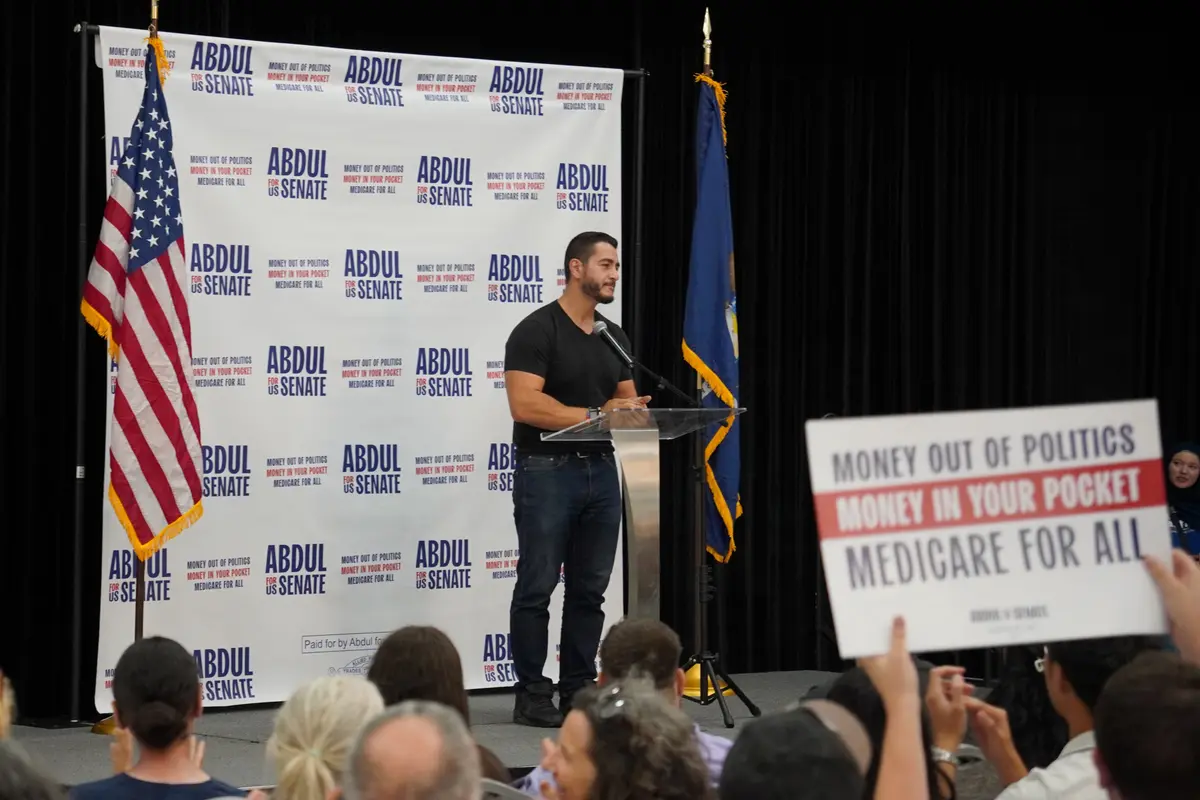 An Abdul El-Sayed supporter holds up a "Money out of Politics; Money in Your Pocket; Medicare for All" sign at a rally in Dearborn, Mich., on July 31, 2026. (Jacob Burg/The Epoch Times)