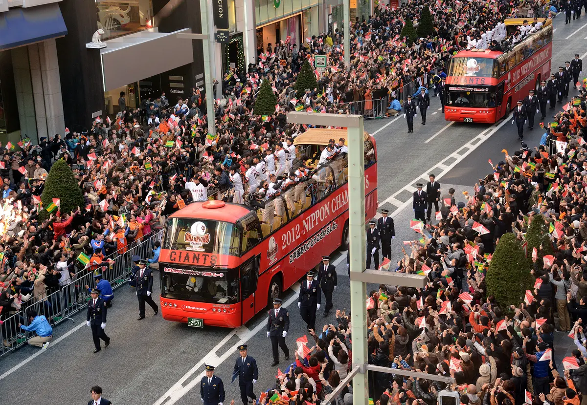 Members of the Tokyo Yomiuri Giants, winners of that year's Japan Series, wave from open-top buses during a parade to celebrate their victory in the Ginza shopping district in Tokyo, Japan, on Nov. 25, 2012. (YOSHIKAZU TSUNO/AFP/Getty Images)