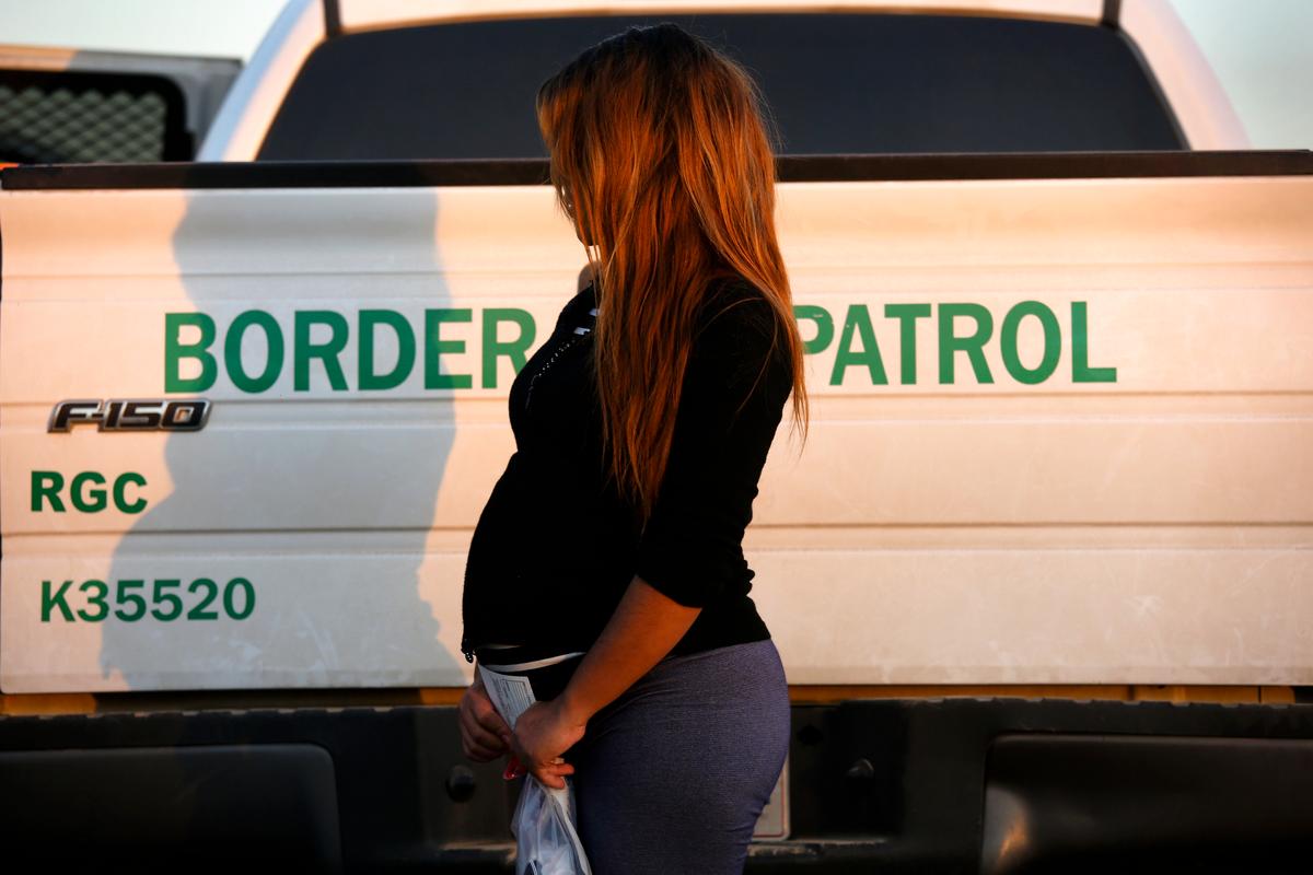 An illegal immigrant from El Salvador, seven months pregnant, stands next to a U.S. Border Patrol truck after turning herself in to border agents near Rio Grande City, Texas, on Dec. 7, 2015. (John Moore/Getty Images)