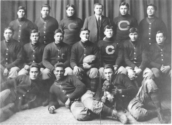 The 1911 Carlisle Indians football team pose with a game ball from the upset of Harvard. Coach "Pop" Warner (standing, 3rd R) and Jim Thorpe (seated, 3rd R) are pictured. (Public Domain)