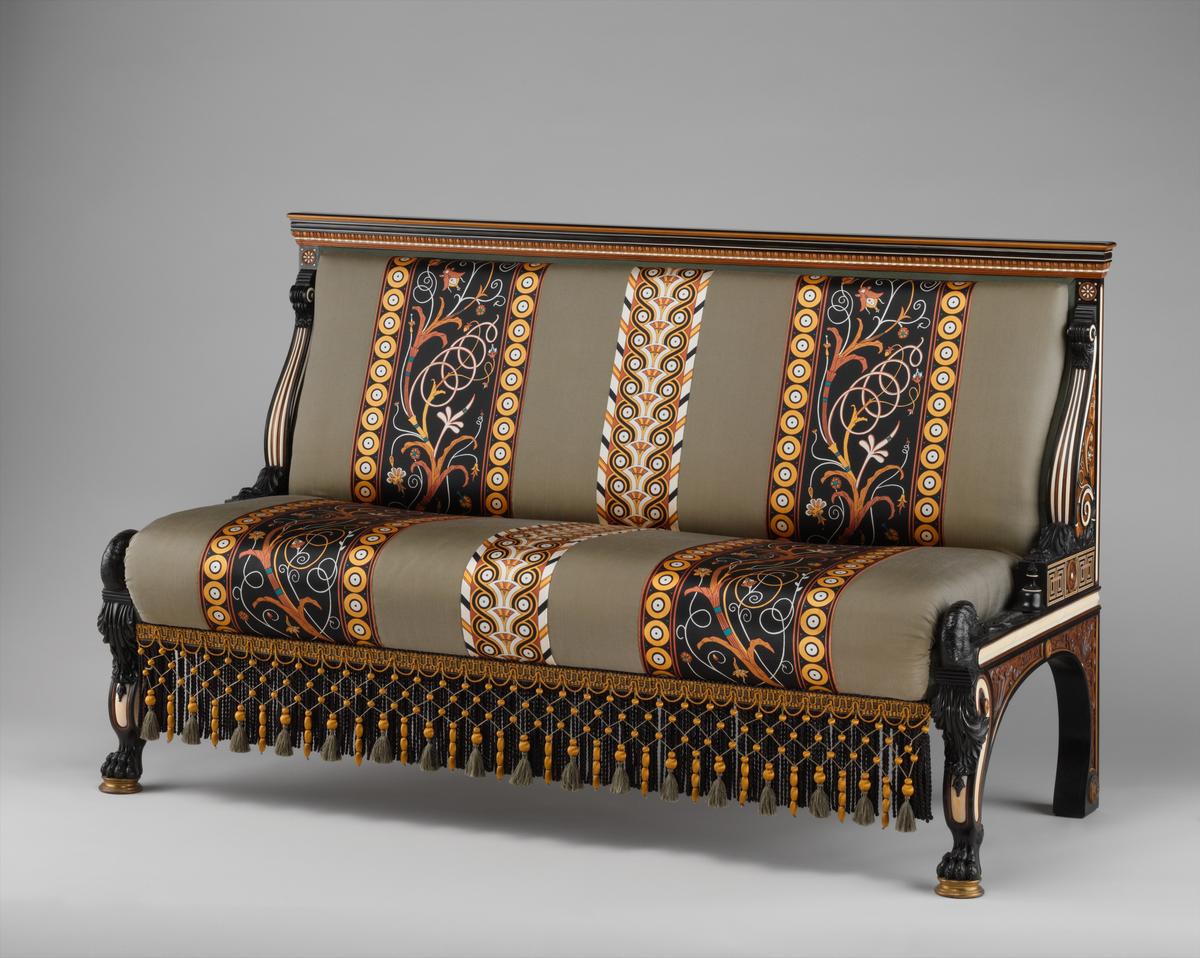 Settee, circa 1885, Designed by Sir Lawrence Alma-Tadema and manufactured by Johnstone Norman & Co., London. Ebony, box and sandalwood, cedar, ivory inlay, incrustations of mother-of-pearl and brass; 35 1/2 inches by 58 1/4 inches by 28 inches. Alma-Tadema created it for financier and Met founder Henry G. Marquand's New York mansion; the original embroidered upholstery was replaced with a specially commissioned silkscreened fabric that evokes the historic design. Metropolitan Museum of Art, New York City. (Public Domain)