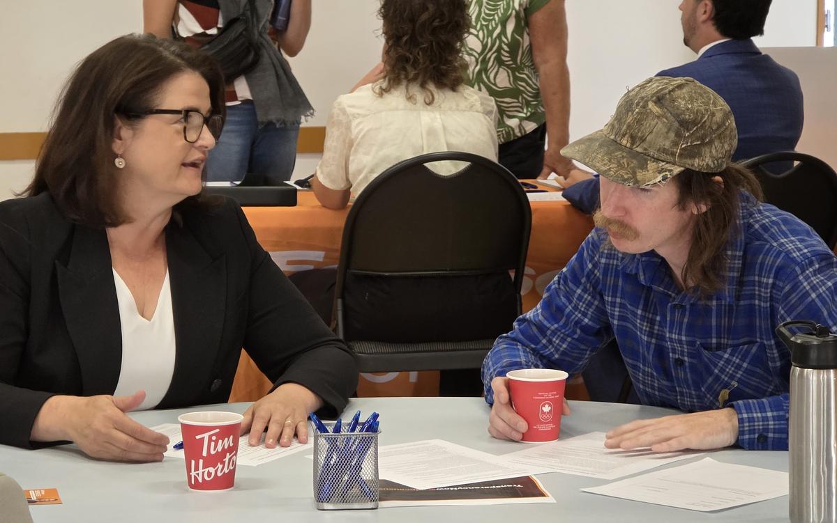 Saskatchewan NDP leader Carla Beck (L) speaks with Moose Jaw resident Levi Vatamaniuk about his concerns about a proposed AI data centre at an open house in Moose Jaw, Sask., on Aug. 11, 2026. (Jason G. Antonio/The Epoch Times)