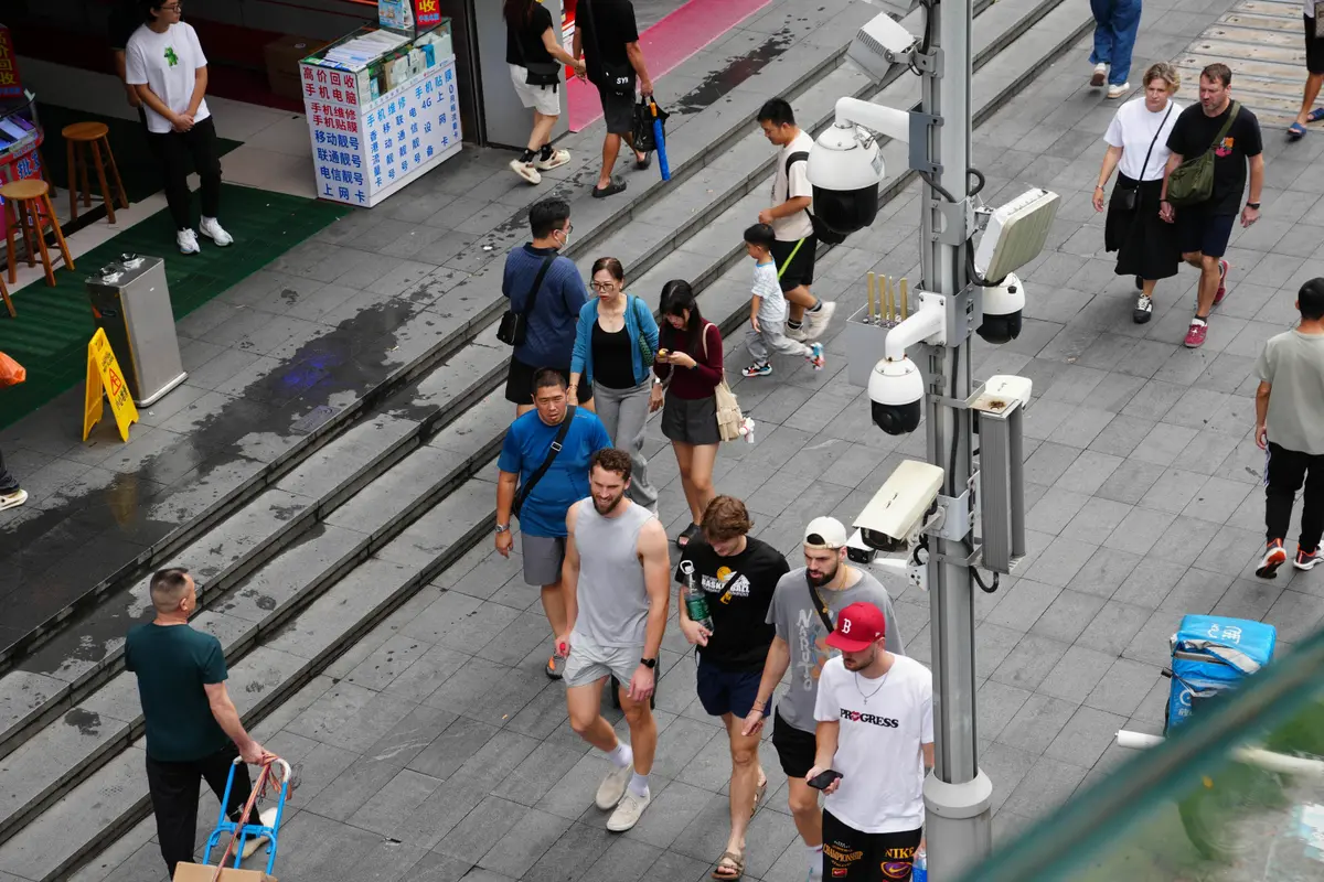 International visitors and pedestrians walk past surveillance cameras in a busy commercial area of Huaqiangbei, Shenzhen, Guangdong, China, on Sept. 5, 2025. (MAUZART/Shutterstock)