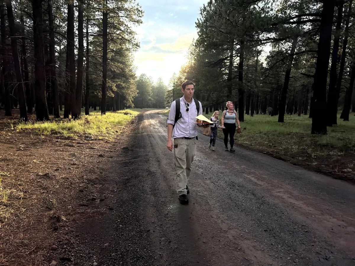 Arizona Mushroom Society Executive Director Mike Dechter walks along a forest road followed by amateur mushroom hunters Michelle Lindsay (R) and 7-year-old daughter Jovie on Aug. 14, 2026. (Allan Stein/The Epoch Times)