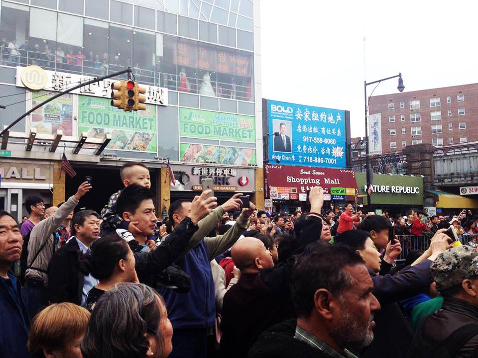 Flushing locals watch and record video of the April 23 parade. (Leo Timm/Epoch Times)