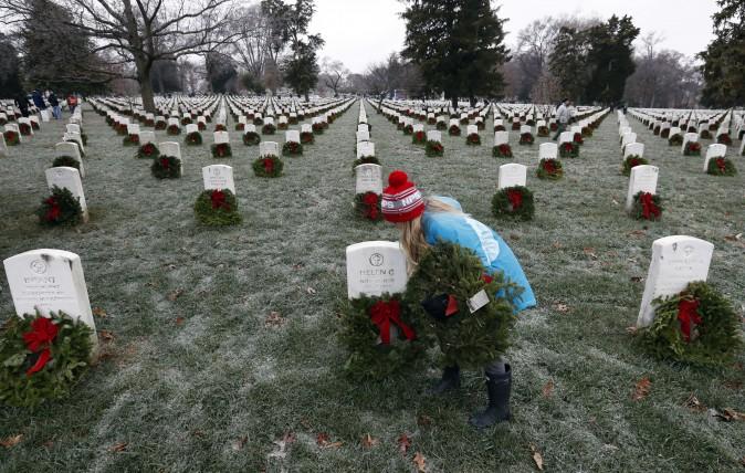Madeline Espinosa, 11, places a wreath at a grave as part of Wreaths Across America at Arlington National Cemetery in Arlington, Va., on Dec. 17, 2016. Organizers estimate more than 245,000 wreaths were placed at graves throughout the cemetery. (AP Photo/Alex Brandon)