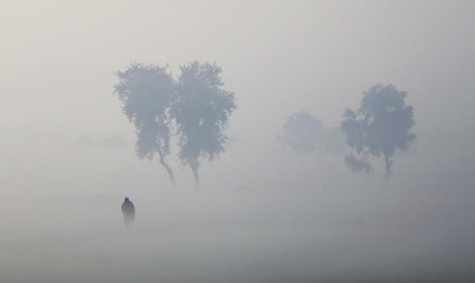 A farmer walks on his field enveloped by thick fog near Hisar, India, on Dec. 23, 2016. (AP Photo/Altaf Qadri)