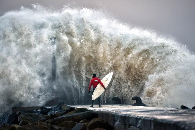 A huge wave crashes against Castlerock pier as professional surfer Al Mennie waits on a break in the swell on in Coleraine, Ireland, on Dec. 22. Storm Barbara is expected to cause major travel disruption when it hits northern parts of the UK later with 90mph winds predicted. (Charles McQuillan/Getty Images)