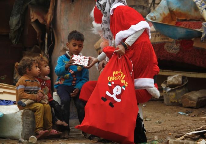 An odontology student dressed in a Santa Claus outfit distributes gifts to impoverished children outside their shanty home in Najaf, Iraq, on Dec. 25, 2016. (Haidar Hamdani/AFP/Getty Images)