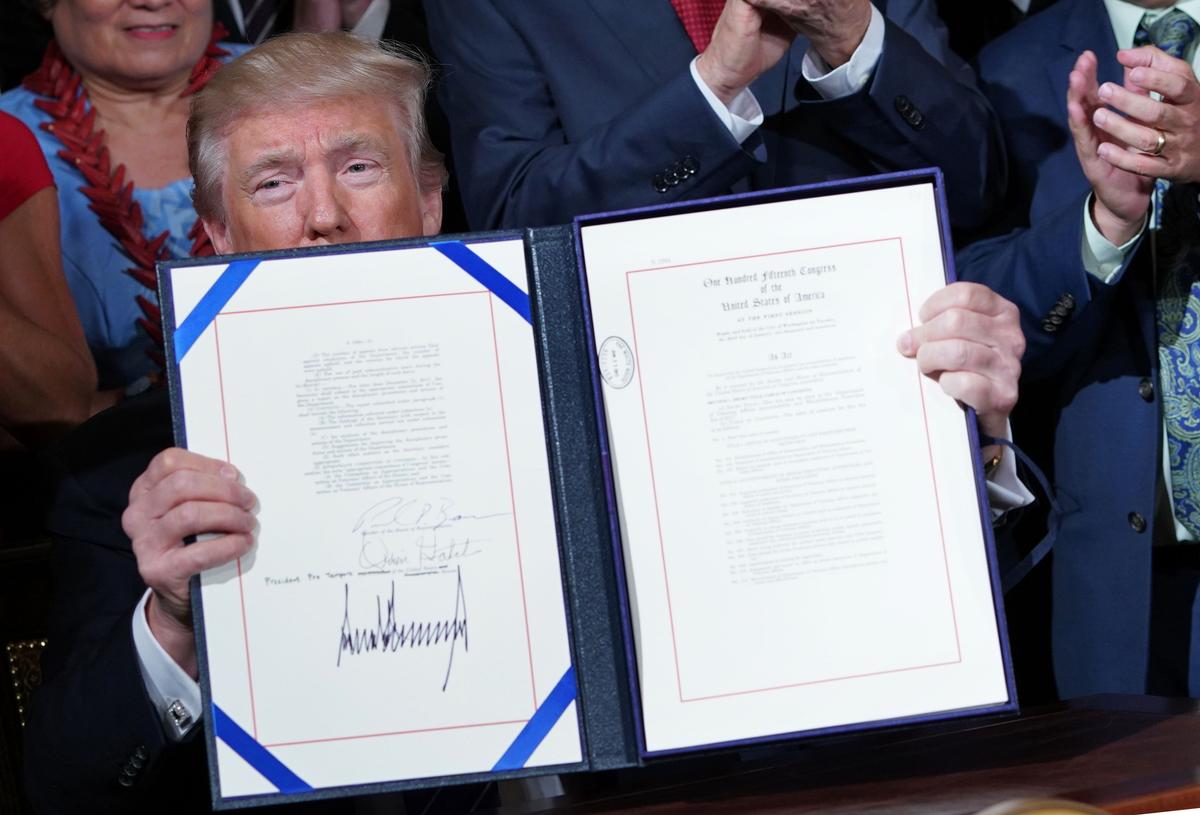 President Donald Trump holds up the bill after signing the Department of Veterans Affairs Accountability and Whistleblower Protection Act of 2017, in the East Room of the White House in Washington on June 23, 2017. (MANDEL NGAN/AFP/Getty Images)