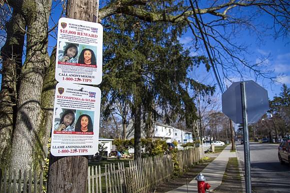 Signs offering a reward for information regarding the murders of Nisa Mickens (L) and Kayla Cuevas are posted near Brentwood High School, where they studied, in Suffolk County, N.Y., on March 29. (Samira Bouaou/The Epoch Times)