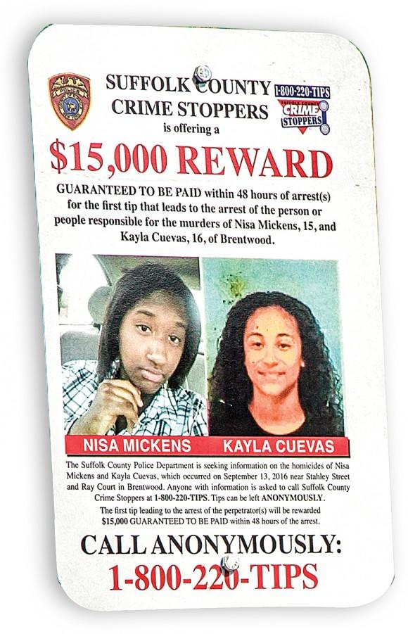 Signs offering a reward for information regarding the murders of Nisa Mickens (L) and Kayla Cuevas are posted near Brentwood High School, where they studied, in Suffolk County, N.Y., on March 29.