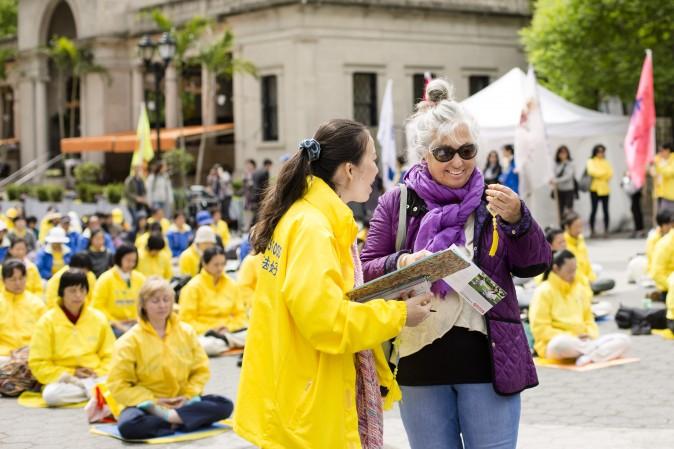 A Falun Dafa practitioner distributes origami lotus flowers to passerby. (Samira Bouaou/The Epoch Times)
