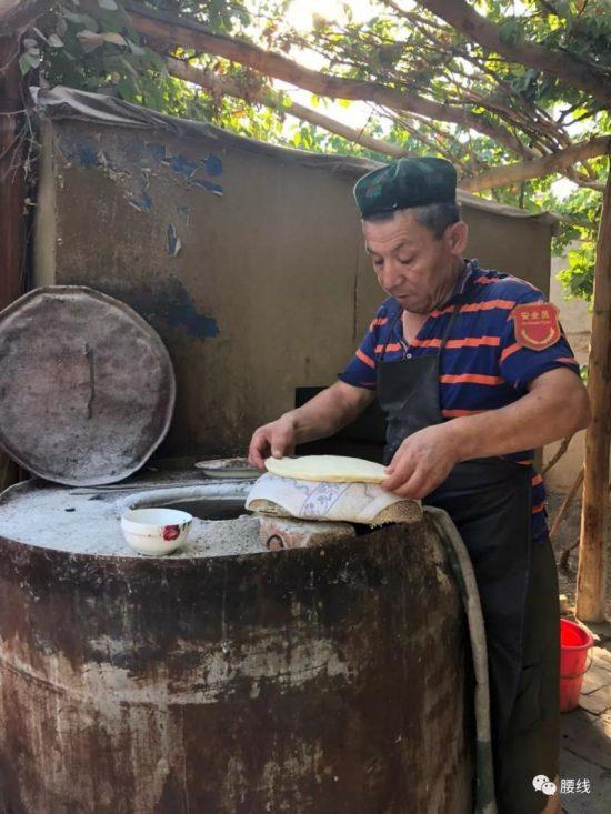 A Uyghur wearing a red security armband is making flat bread in Xinjiang, China on June 2019. (WeChat user "Sang Sang")