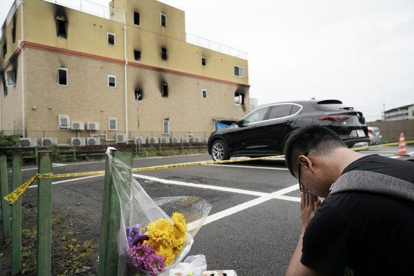 A man prays for the victims after placing flowers outside the Kyoto Animation Studio building consumed in an arson attack, in Kyoto, Japan, on July 19, 2019. (Jae C. Hong/AP Photo)