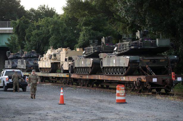 Two M1A1 Abrams tanks and other military vehicles sit on guarded rail cars at a rail yard in Washington on July 2, 2019. (Mark Wilson/Getty Images)