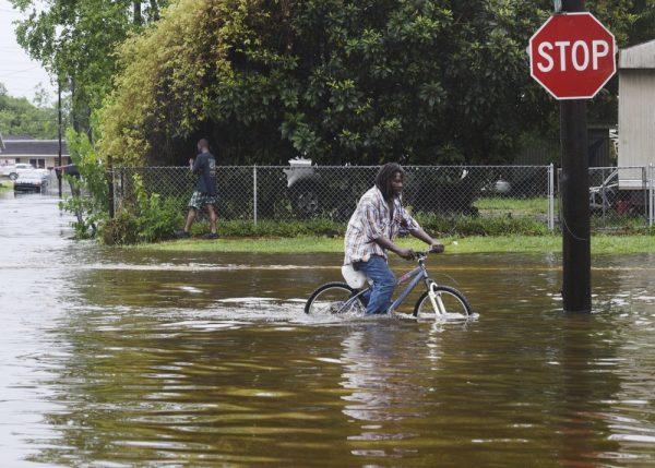 A man tries to bike through the flooding from the rains of storm Barry on LA Hwy 675 in New Iberia, La., on July 14, 2019. (Henrietta Wildsmith/The Shreveport Times via AP)