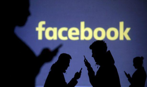 Silhouettes of mobile users are seen next to a screen projection of the Facebook logo in this picture illustration taken on March 28, 2018. (Dado Ruvic/Illustration/Reuters)