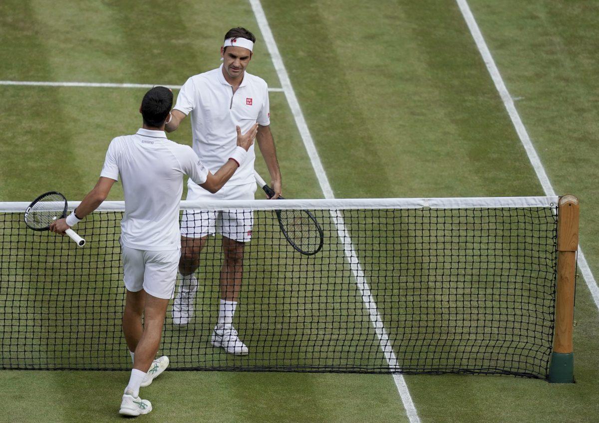 Serbia's Novak Djokovic (L) shakes hands with Switzerland's Roger Federer (R) after he defeats him during the men's singles final match of the Wimbledon Tennis Championships in London, on July 14, 2019. (Will Oliver/Pool Photo via AP)