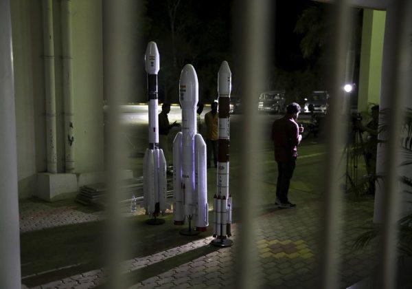 An Indian Video journalist reports standing next to models of Indian Space Research Organization (ISRO)'s Geosynchronous Satellite launch Vehicle (GSLV) MkIII at Satish Dhawan Space Center after the Chandrayaan-2 mission was aborted at the last minute at Sriharikota, in southern India, on July 15, 2019. (Manish Swarup/AP Photo)