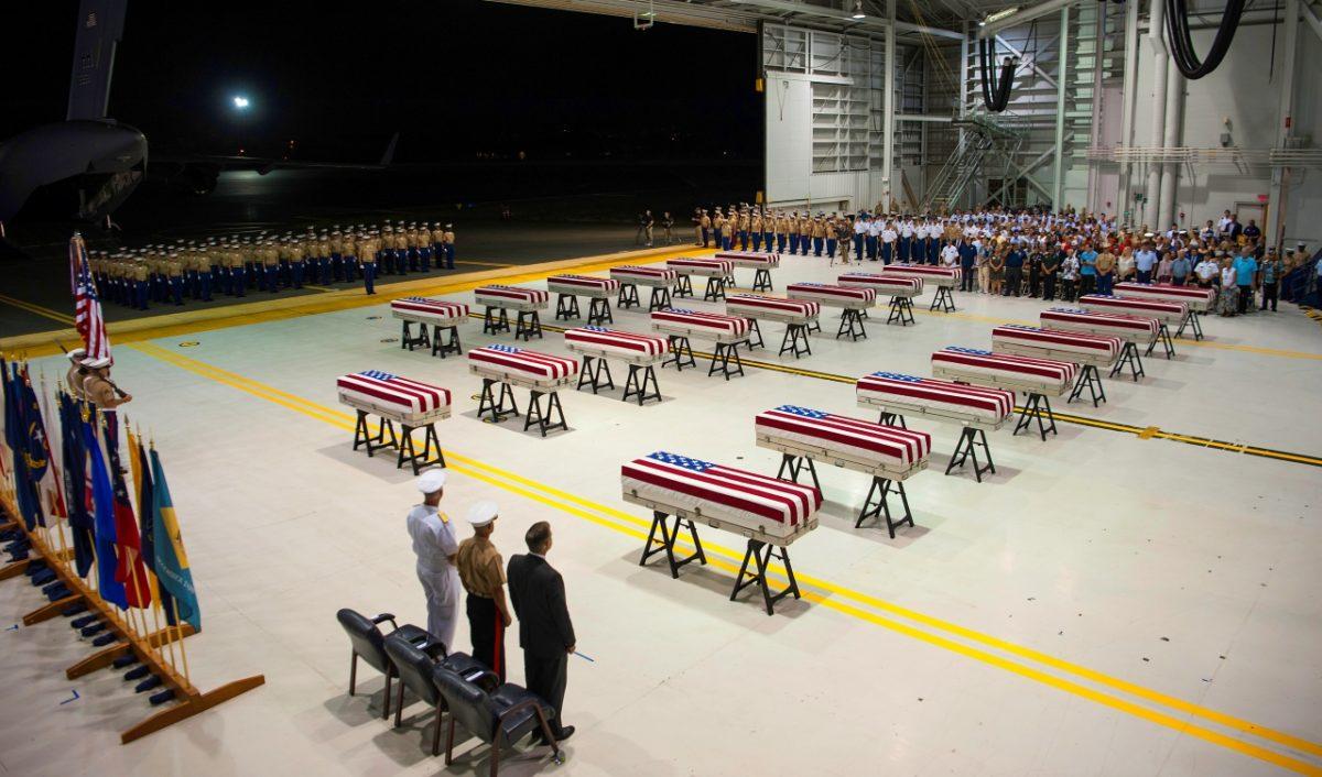 Service members and guests stand as "Taps" is played over transfer cases carrying the possible remains of unidentified service members lost in the Battle of Tarawa during World War II on July 17, 2019. (Sgt. Jacqueline Clifford/U.S. Marine Corps via AP)