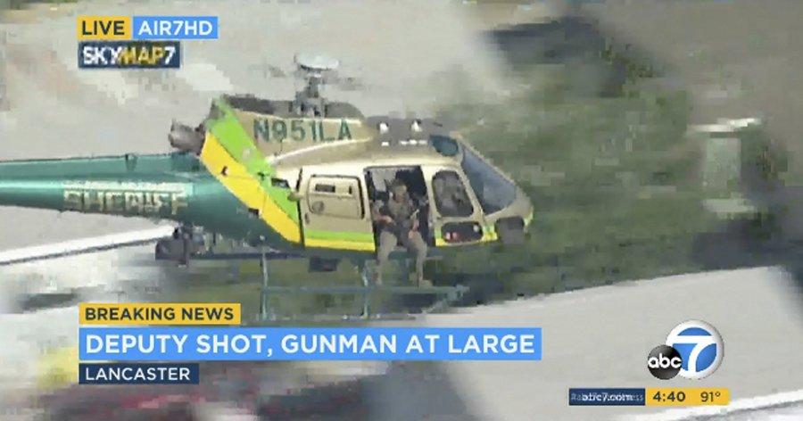 This photo taken from video provided by KABC-TV shows a sheriff's department helicopter with a sniper in an open door searching for a gunman at large in Lancaster, Calif. on Aug. 21, 2019. (KABC-TV via AP)