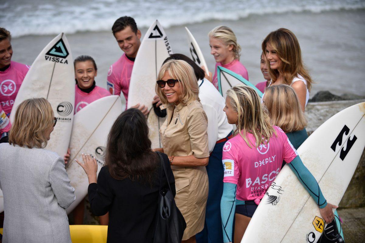 First Lady Melania Trump (R) looks towards Brigitte Macron, wife of the French President (C) during a meeting with surfers at the Cote des Basques beach, in Biarritz, south-western France, on Aug. 26, 2019, on the third and final day of the annual G7 summit. (JULIEN DE ROSA/AFP/Getty Images)