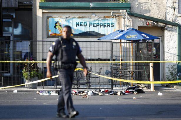 A police officer walks by a shoe pile outside the scene of a mass killing outside Ned Peppers bar in Dayton, Ohio, on Aug. 4, 2019. (John Minchillo/AP Photo)