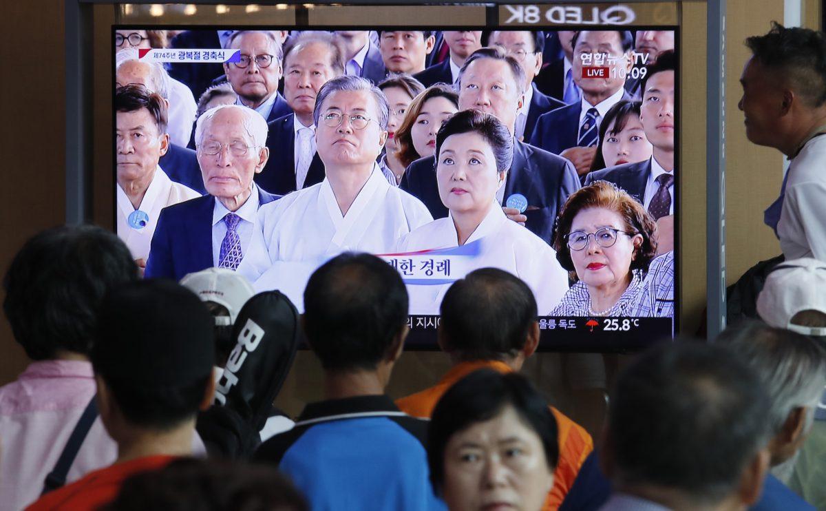 People watch a TV screen showing a live broadcast of South Korean President Moon Jae-in, center left, and his wife Kim Jung-sook during a ceremony to celebrate the Korean Liberation Day, marking the 74th anniversary of Korea's liberation from the Japanese colonial rule, at the Seoul Railway Station in Seoul, South Korea, on Aug. 15, 2019. The signs read: "Korean Liberation Day."(AP Photo/Ahn Young-joon)