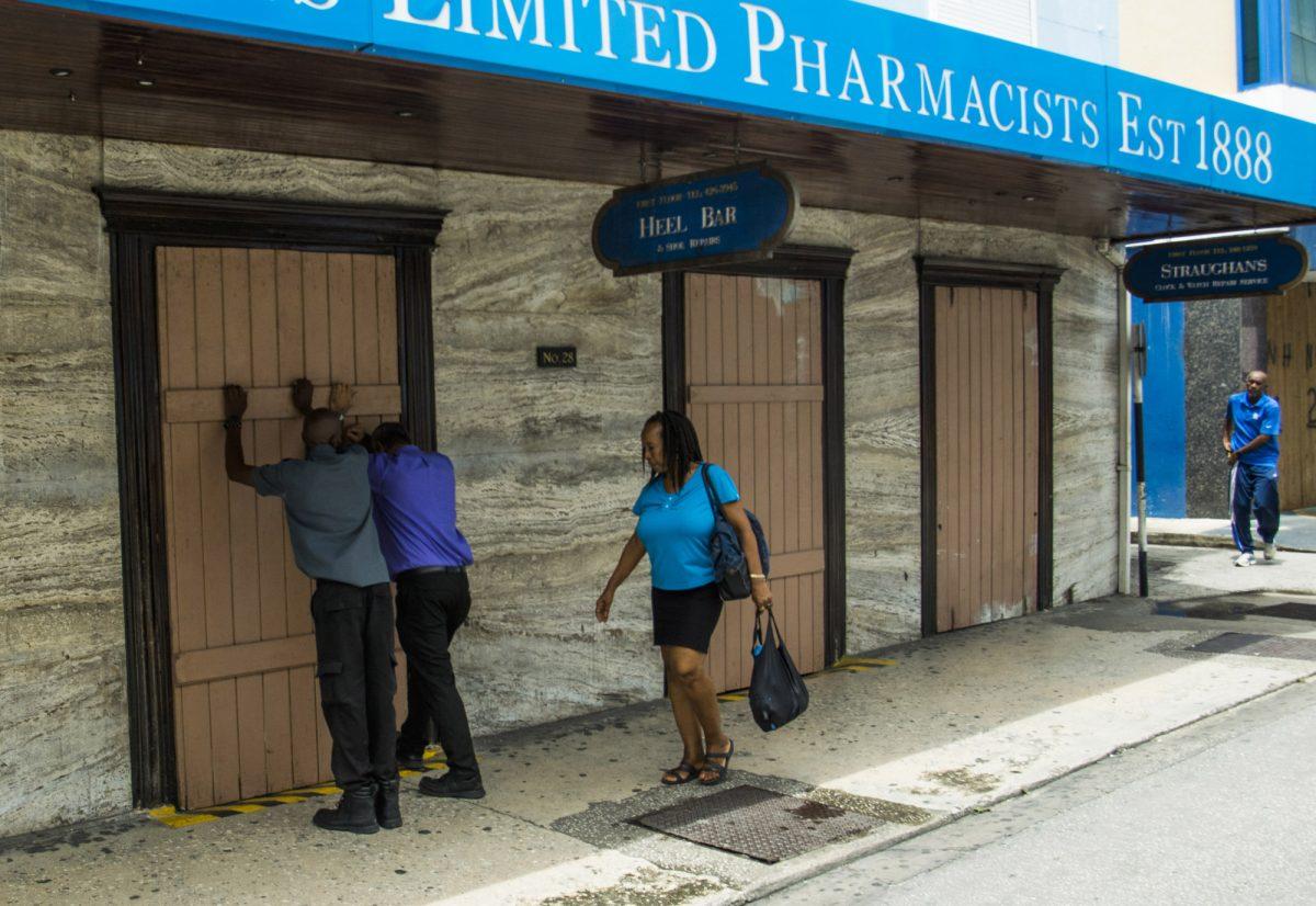 Residents board up a storefront pharmacy as they prepare for the arrival of Tropical Storm Dorian, in Bridgetown, Barbados on Aug. 26, 2019. (AP Photo/Chris Brandis)
