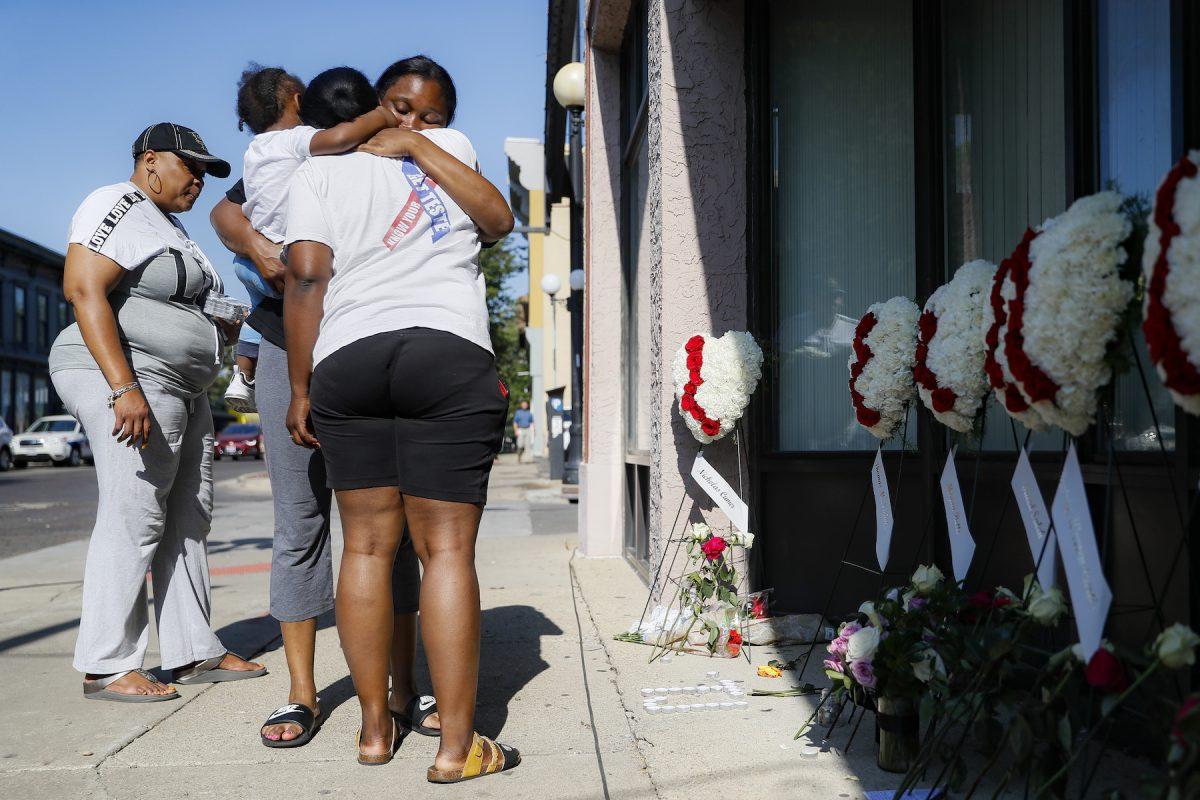 Family members of slain mass shooting victim Thomas “TJ” McNichols, from left, Donna Johnson, aunt, and sisters Jamila and Finesse McNichols, mourn beside a memorial near the scene of the crime, in Dayton, Ohio, Aug. 5, 2019. (AP Photo/John Minchillo)