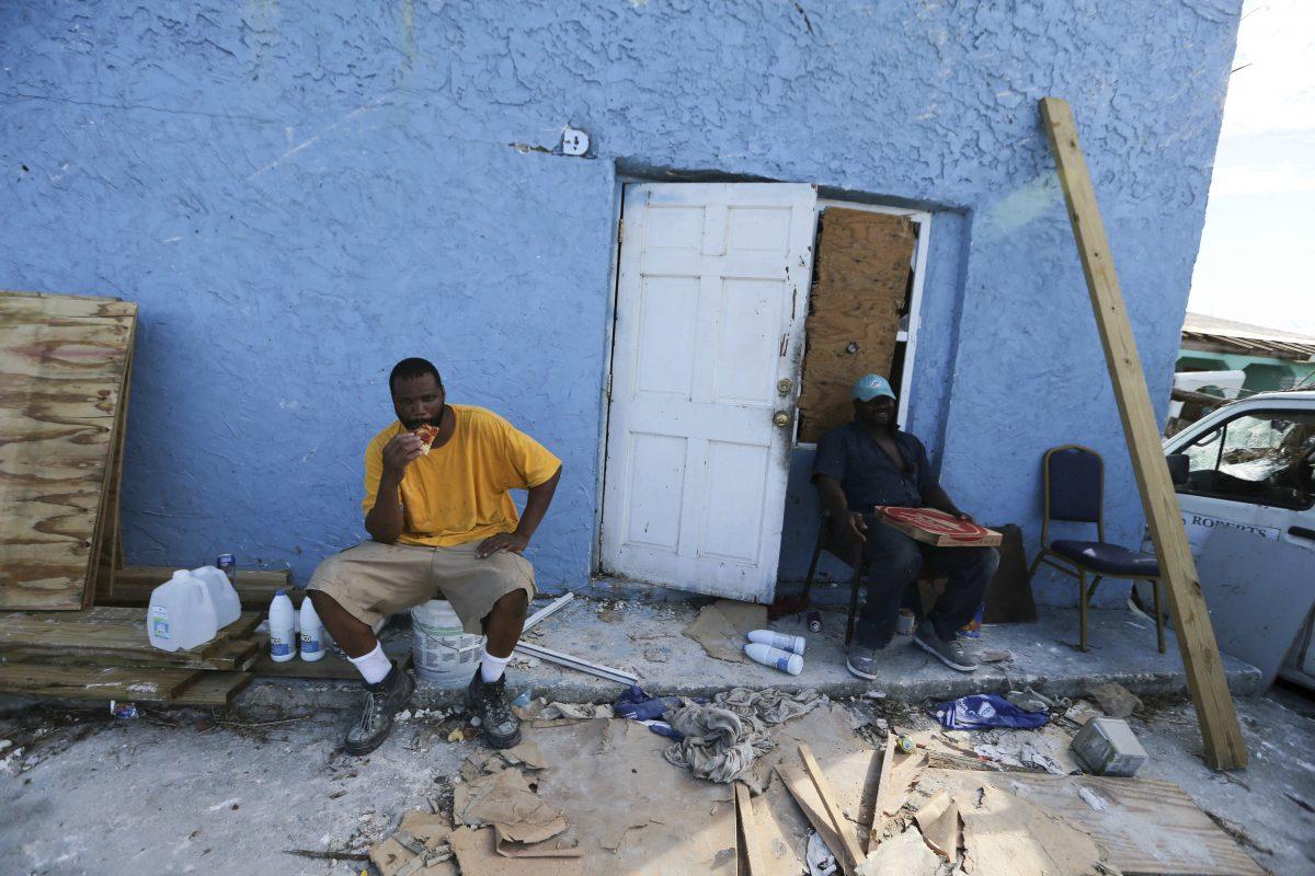 Men eat pizza delivered by volunteers, at a town destroyed by Hurricane Dorian in Marsh Harbor, Abaco Island, Bahamas, on Sept. 6, 2019. (Fernando Llano/AP Photo)