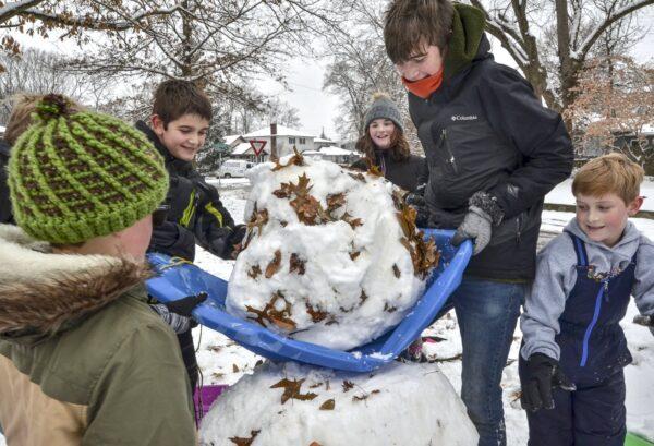 Andrew Kinne (C) helps a group of kids lift a snowball to create a snowman in Terre Haute, Ind., on Dec. 16, 2019. (Austen Leake/The Tribune-Star via AP)