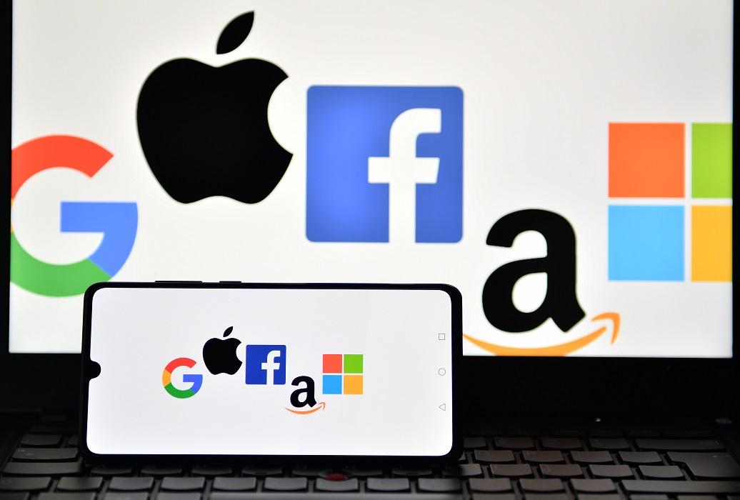 An illustration picture taken in London shows the logos of Google, Apple, Facebook, Amazon and Microsoft displayed on a mobile phone and a laptop screen on Dec. 18, 2020. (JUSTIN TALLIS/AFP via Getty Images)