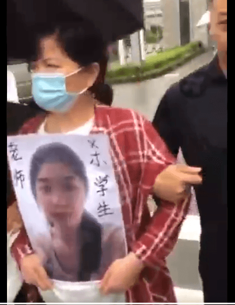 A screenshot of a video posted on Chinese social media showing three relatives of the victim holding a large photo of her outside the gate of Ningbo Institute of Technology, where they demanded an explanation from the school. (Screenshot via The Epoch Times)
