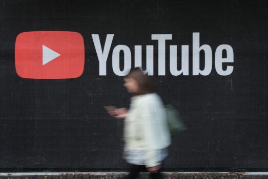 A woman with a smartphone walks past a billboard advertisement for YouTube in Berlin on Sept. 27, 2019. (Sean Gallup/Getty Images)