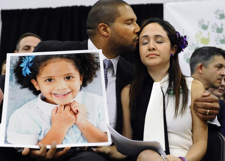 Jimmy Greene, left, kisses his wife Nelba Marquez-Greene as he holds a portrait of their daughter, Sandy Hook School shooting victim Ana Marquez-Greene, at a news conference at Edmond Town Hall in Newtown, Conn in this file photo. (AP Photo/Jessica Hill)
