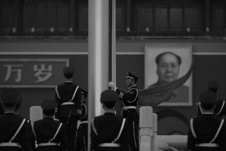 A paramilitary police officer collects the PRC flag in front of Mao Zedong's portrait in Beijing's Tiananmen Square on March 2. China Central Television recently quoted Mao saying that he was willing to see hundreds of millions of Chinese killed. (Feng Li/Getty Images)