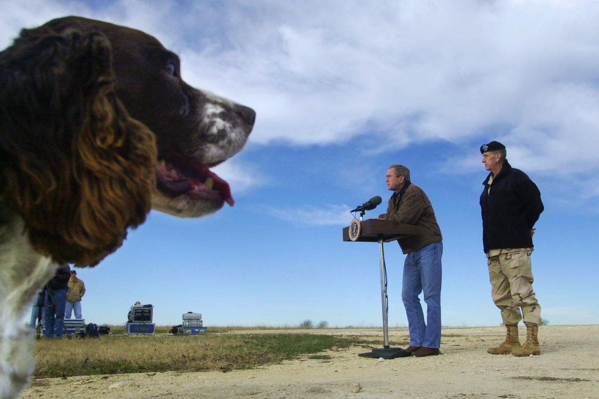 With his dog Spot, an English Springer Spaniel, looking on, President Bush, standing with Afghan war commander Army Gen. Tommy Franks, answers questions during a news conference at his ranch in Crawford, Texas, Friday, Dec. 28, 2001. (AP Photo/Susan Walsh)