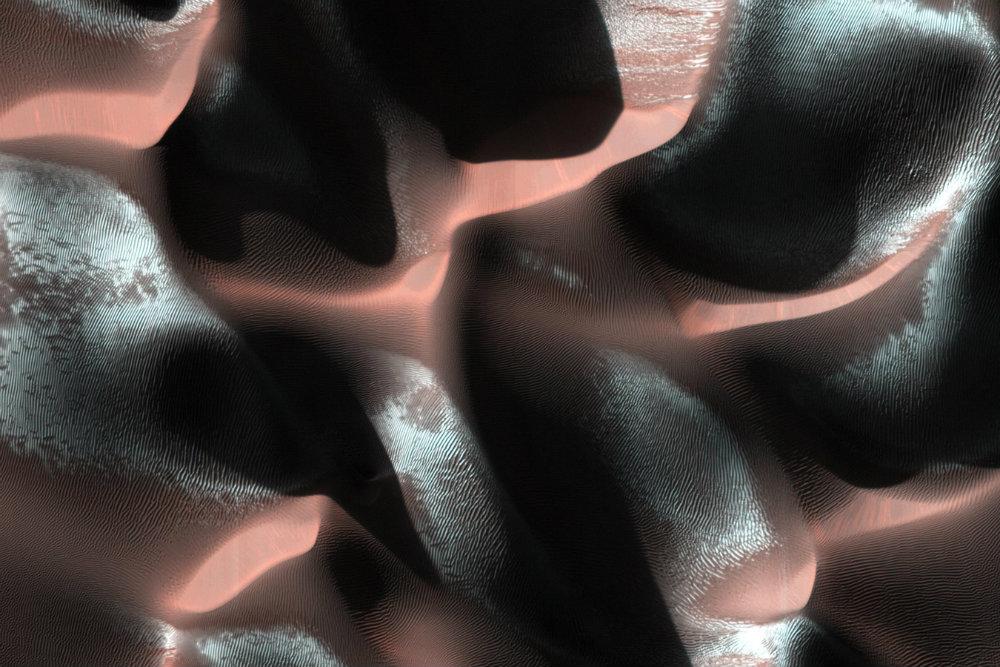 This image of a sand dune field on Mars in a Southern highlands crater was acquired when the Sun was just 5 degrees above the horizon. As a result, the image is mostly shadows, with sharply-delineated dune crests sticking up into the sunlight. The especially bright patches -- bluish in enhanced color -- are due to seasonal frost that is accumulating as this hemisphere approaches winter. (NASA/JPL-Caltech/Univ. of Arizona)
